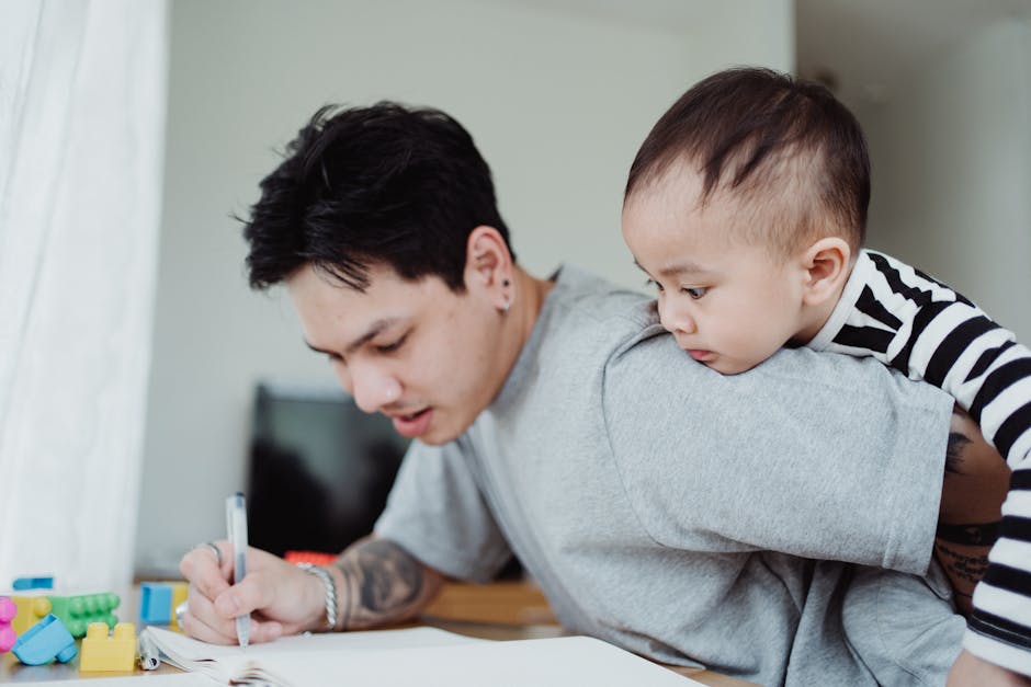 Un père jonglant avec son travail tout en portant son enfant, mettant en lumière les défis de la parentalité.