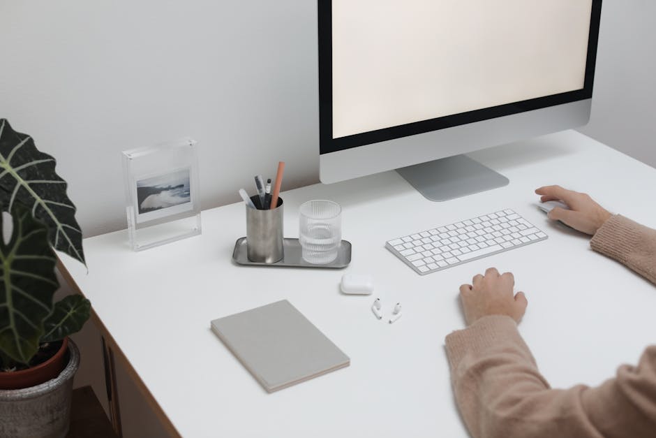 Vue en plongée d’une personne sans visage assise à une table avec des gadgets sans fil et un ordinateur