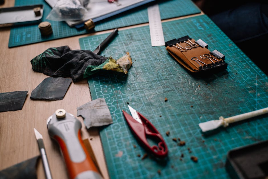 A cluttered workspace featuring cutting mats, tools, and crafting materials for DIY projects.