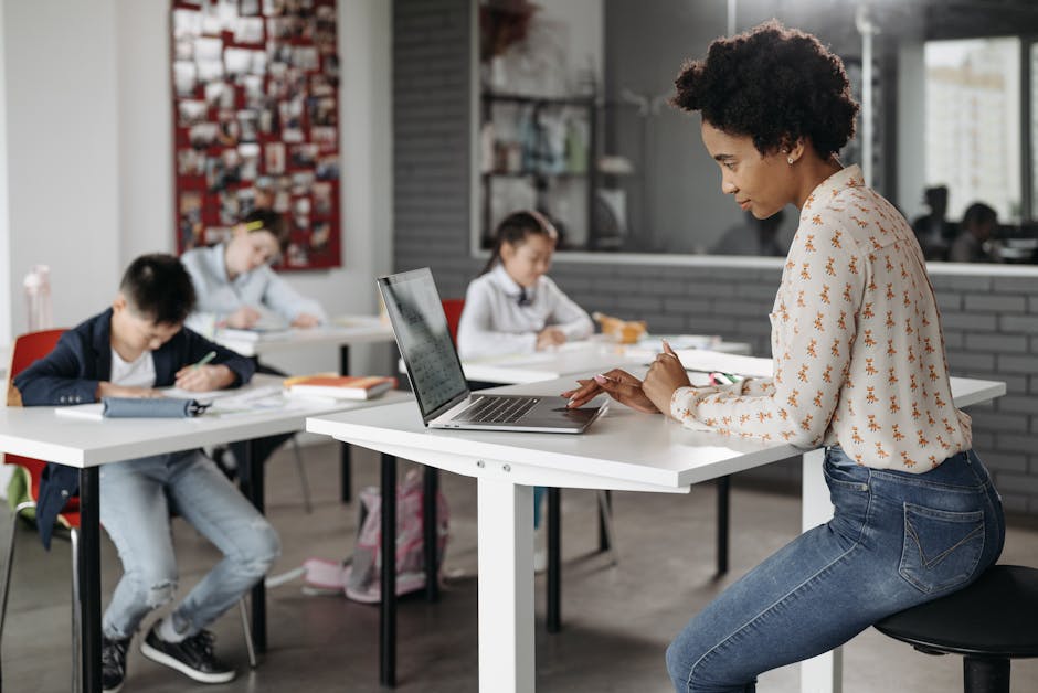 Focused teacher with students working at desks in an indoor classroom environment.