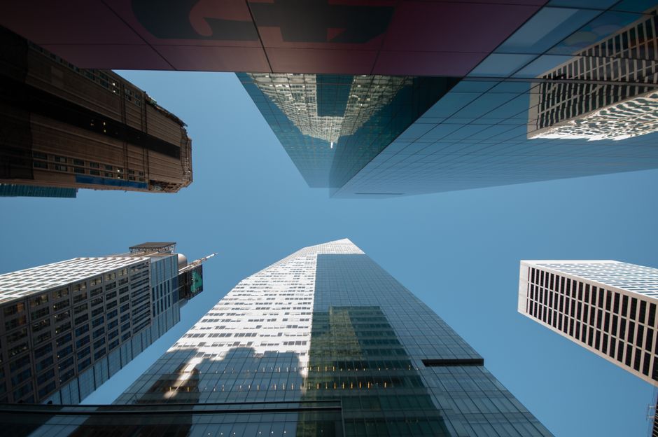 Dynamische Aufsicht nach oben auf moderne Wolkenkratzer unter klarem blauem Himmel, urbanes Architektur-Motiv.