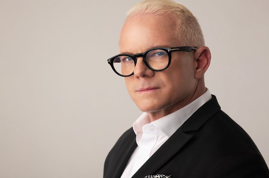 Portrait élégant d’un homme adulte blond portant des lunettes et un costume, parfait pour un usage corporate ou mode.
