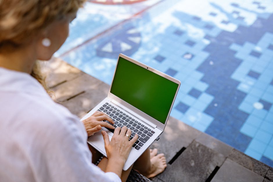 Relaxed work environment with a laptop and person typing on a bed, enjoying comfort while working.