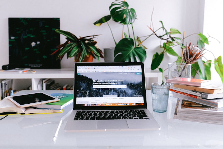 A clean and bright home office desk with a laptop, books, and plants, perfect for freelancers or remote work.
