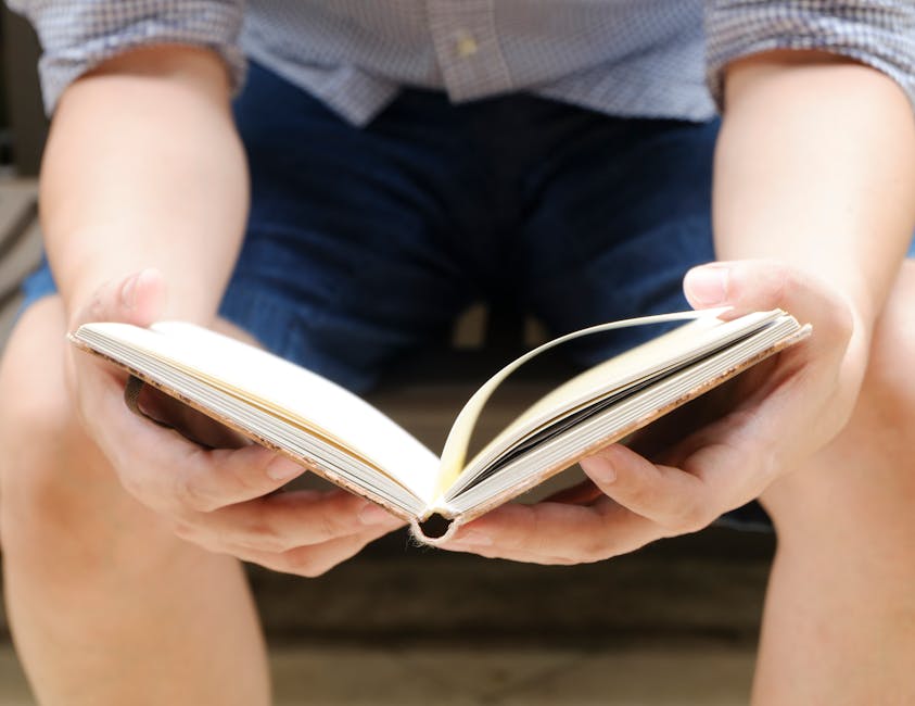 A man casually reads a book while sitting outdoors, showcasing a relaxed lifestyle.