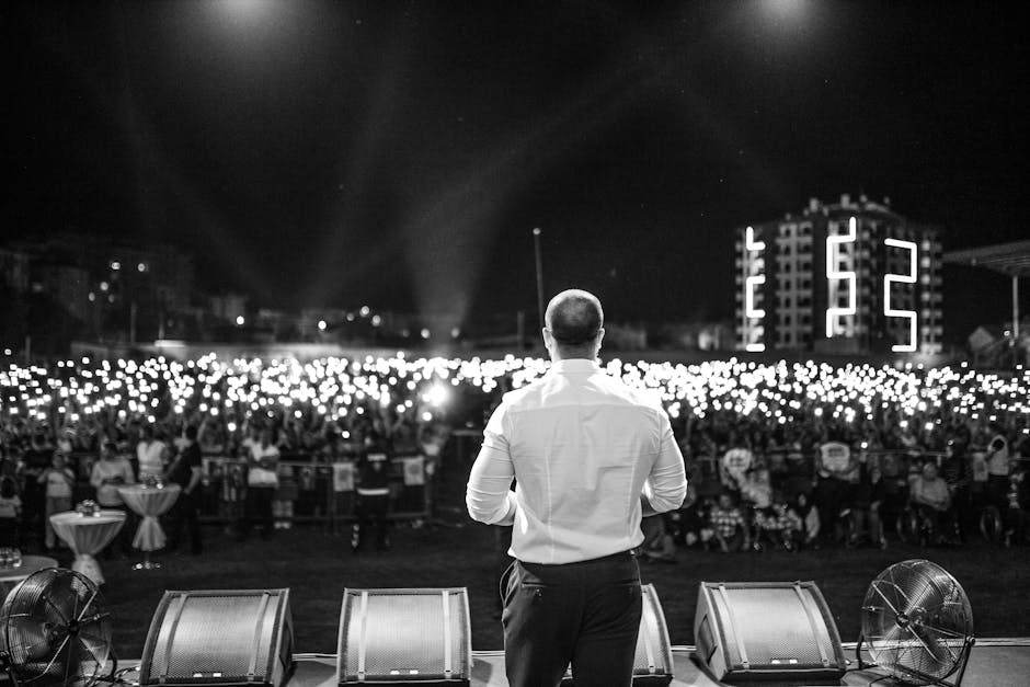 A performer faces a large crowd holding lights, capturing a moment of connection and excitement.