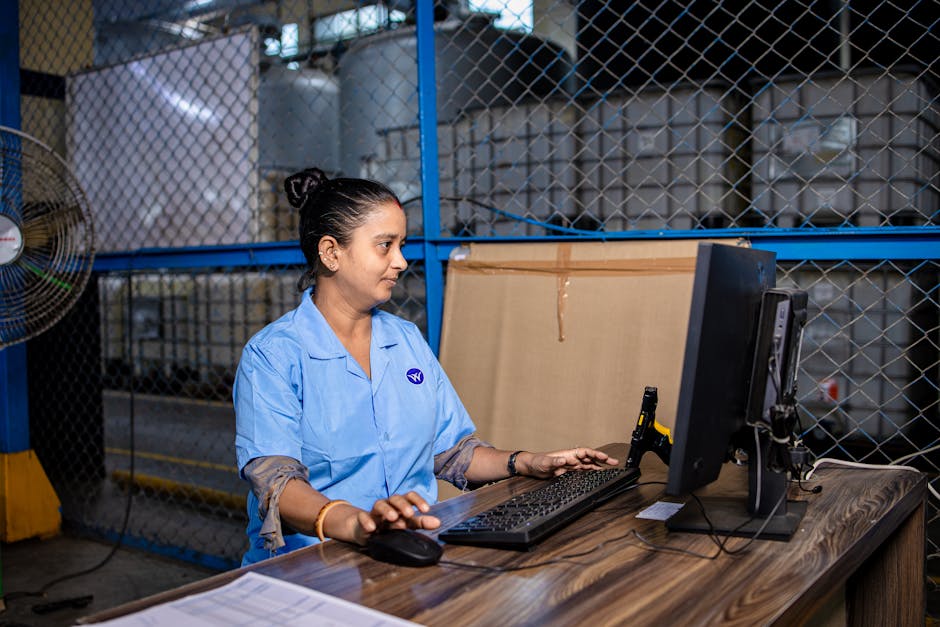A female factory worker using a computer in an industrial environment.