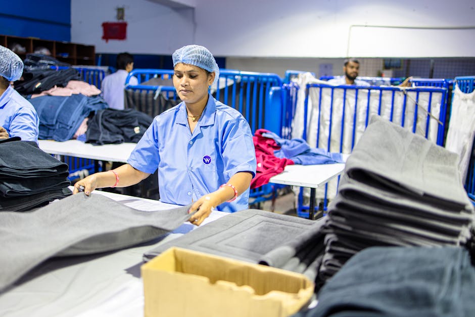 Workers folding fabric in a textile factory, highlighting industrial labor.